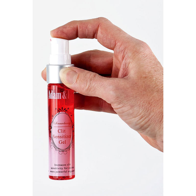 A hand holds a pink and red bottle labeled Adam & Eve Clit Sensitiser Gel - Strawberry Flavoured Female Enhancer, featuring a pump dispenser. It promises to enhance clitoral sensitivity, boosting pleasure and orgasmic frequency, set against a simple white background.