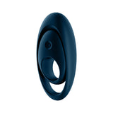 A sleek, oval-shaped dark blue object with a smooth surface and a hollow circular center, made of body-friendly silicone. The smaller ovals power button symbol hints at its modern design—likely the Satisfyer Glorious Duo, a USB rechargeable cock & balls ring.