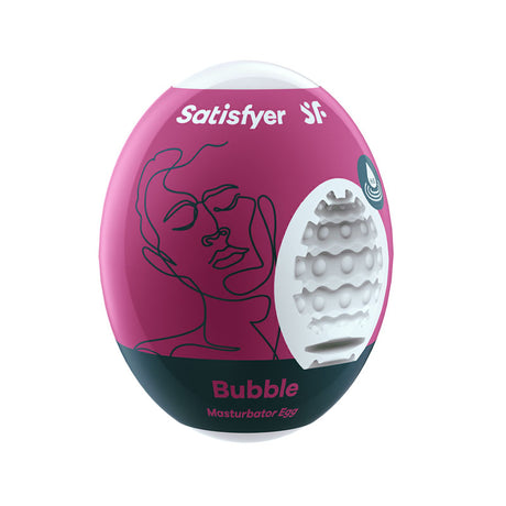 The Satisfyer Masturbator Egg - Bubbles packaging, pink and black with a minimalist face line drawing, showcases a cut-out revealing its textured cyber-skin interior. The brand name and vibration icon are printed on top, making it an ideal travel companion.