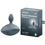 A dark gray Satisfyer Booty Absolute Beginners 4 silicone anal toy, featuring USB rechargeable vibration, sits beside its box. The packaging displays the same product image and branding with Anal Training and Unisex, plus a detailed diagram highlighting its vibrating feature.