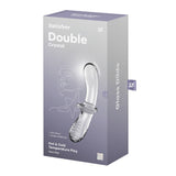 The Satisfyer Double Crystal - Clear Glass Double Ended Dildo box is predominantly gray with white text, featuring a line drawing of a face and product illustrations. The packaging highlights Solid Glass and Hot & Cold Temperature Play.