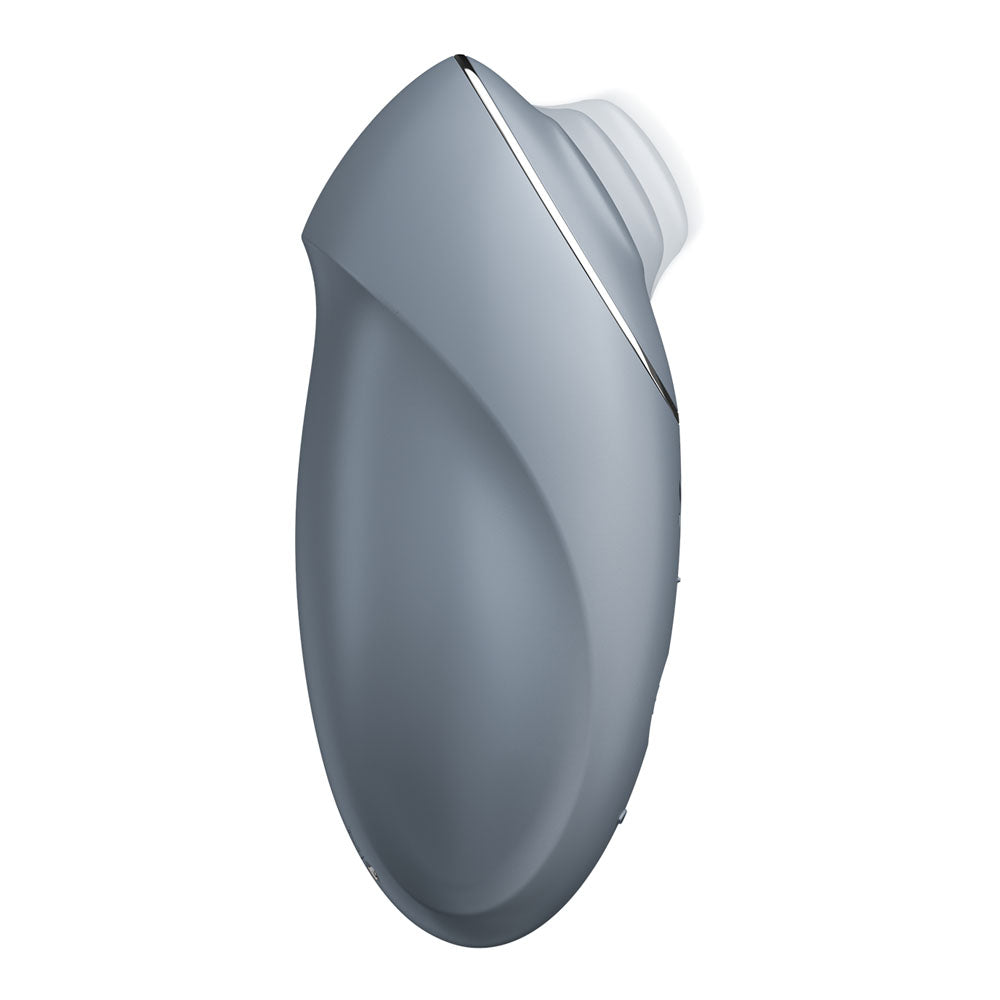 The Satisfyer Tap & Climax 1 is a sleek, ergonomic bluegrey lay-on vibrator with smooth curves, a small circular opening at the top, and a metallic side accent. Its handheld shape ensures comfort and ease of use for clitoral stimulation. USB rechargeable for convenience.