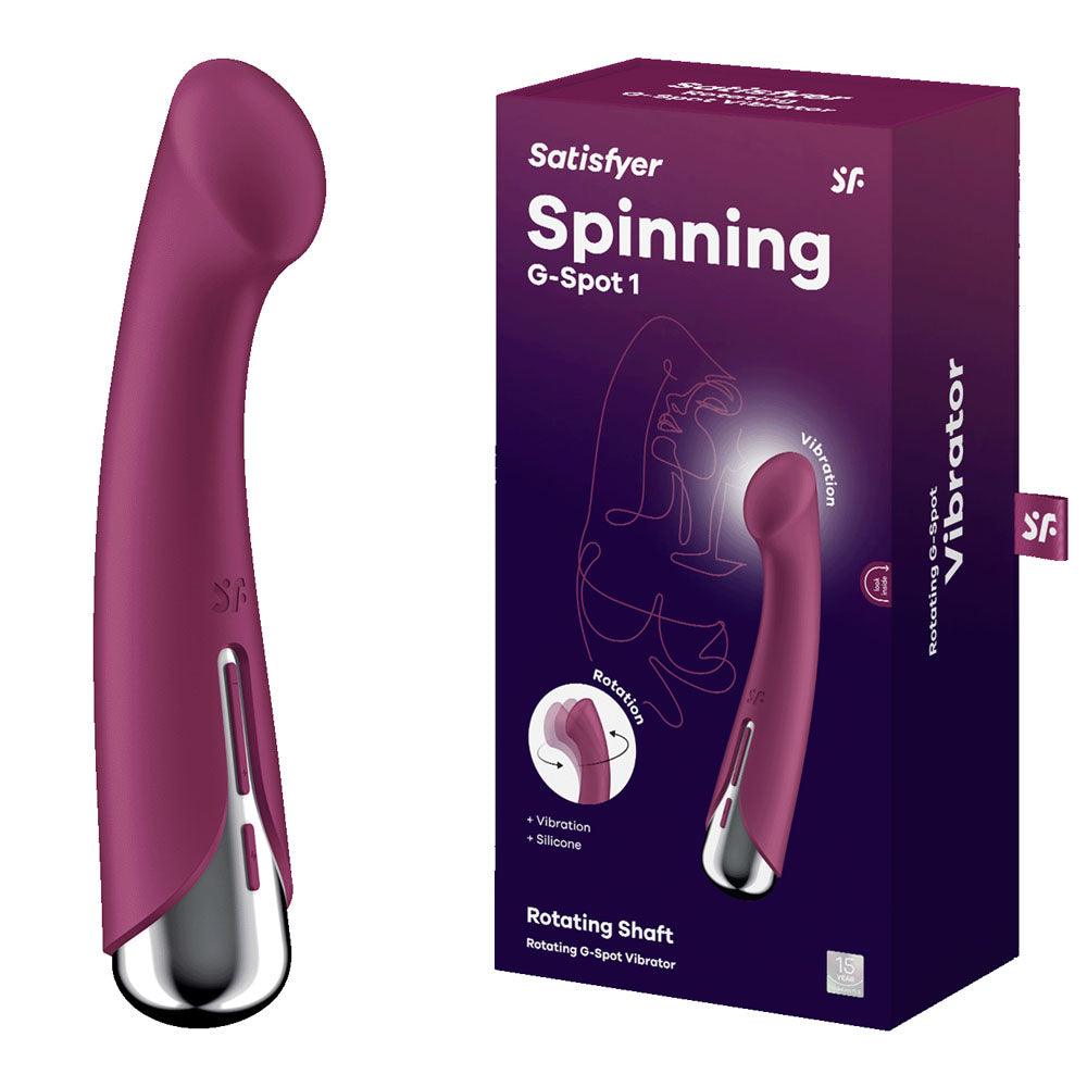 A red curved-tip vibrator, USB rechargeable, sits beside its maroon box, showcasing the Satisfyer Spinning G-Spot 1. The packaging highlights its waterproof and rotating features for enhanced pleasure.