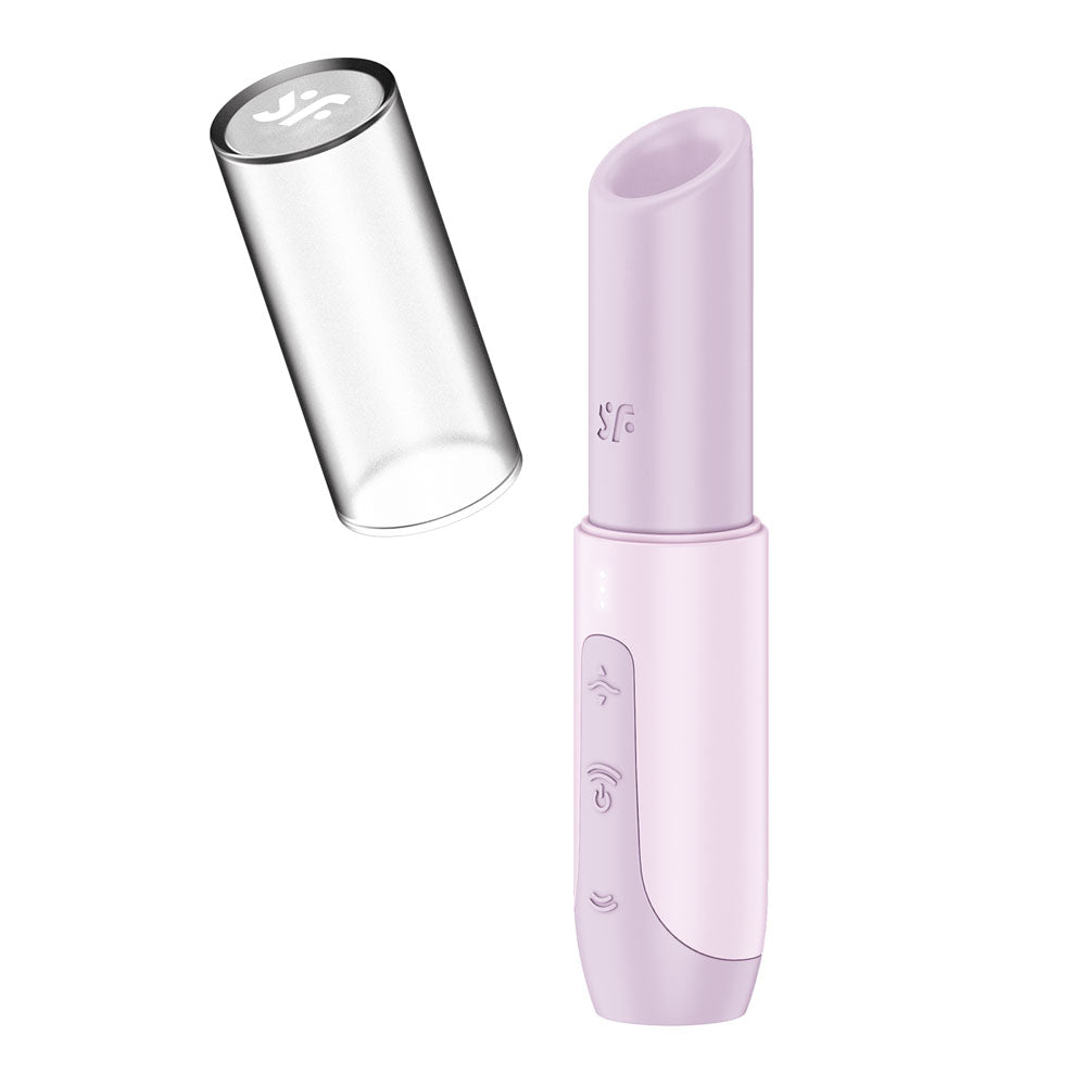 The Satisfyer Secret Kiss Lilac is a compact electronic personal care device, designed for travel with a discreet look. Featuring a button interface with symbols, it has a silver semi-transparent cap with engraving and a cylindrical shape with a tapered open end.