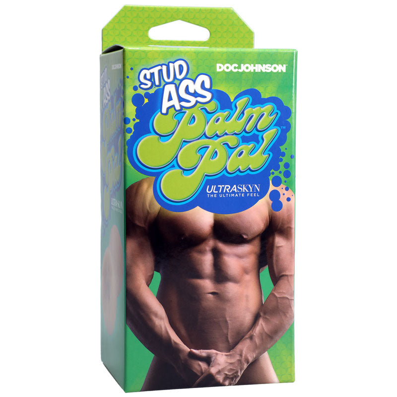 A green rectangular box with blue accents shows a shirtless, muscular male torso. Stud Ass Palm Pal is in bold white and blue letters. Doc Johnson heads it, while ULTRASKYN, The Ultimate Feel, emphasizes its textured interior for handheld use below.