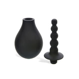 The Adam & Eve Smooth & Easy Silicone Douche in black has a smooth, rounded reservoir and a detachable silicone tip nozzle. Its bulbous segments and flat base ensure easy cleaning, ideal for anal douching, all set against a white background.