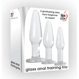 The image shows a box labeled Adam & Eve Glass Anal Training Trio - Clear Glass Butt Plugs - Set of 3 Sizes, featuring three vertically arranged borosilicate glass plugs, highlighting 3 graduating sizes from beginner to expert, ideal for pelvic floor training.