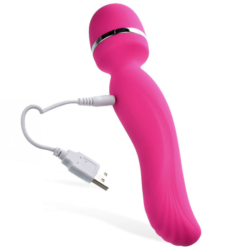 The Adam & Eve Intimate Curves Rechargeable Wand in vibrant pink, with a round head and curved handle accented by silver near the top, comes with a white USB charging cable. Its set against a plain white background.