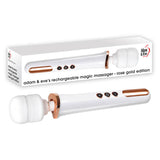 The image displays a white Adam & Eve Rechargeable Magic Massager with rose gold accents, featuring a cylindrical handle and rounded silicone head. Three control buttons adorn the handle, while behind it is a box showing the massager and its name: Adam & Eve Rechargeable Magic Massager.