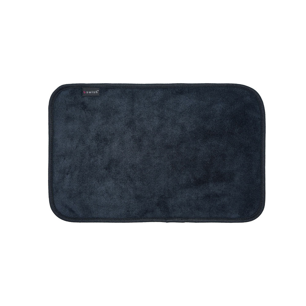 Introducing the B Swish After Sex Towel: a rectangular, dark blue microfiber bath mat featuring rounded corners, a plush texture, and a small black tag with red and white text on the upper left corner. It rests against a plain white background.