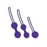 The Bodywand Squeeze 3pc Kegel Training Set features three purple silicone exercise balls. Each ball has dual spheres and a looped handle for easy retrieval, with sizes increasing from right to left, the leftmost being the largest—designed for strengthening pelvic muscles.