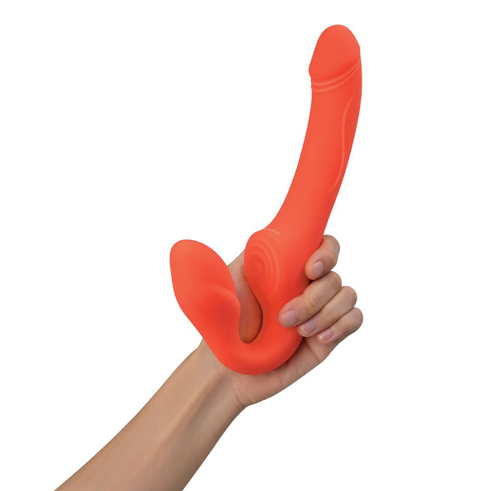 A hand holds the Bodywand ID Access Strapless Strap-On in vibrant orange. One end looks like a vibrating insertable egg with a bulbous tip, while the other is ergonomically curved. Its smooth, flexible silicone makes it ideal as a couples toy.