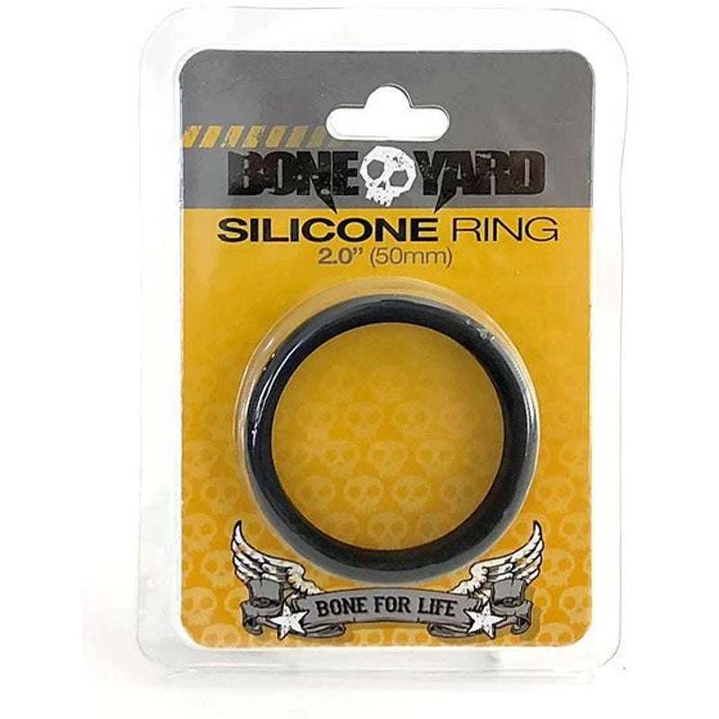 The Boneyard Silicone Ring, also known as the 50mm Black Cock Ring, is a man toy with 3x-stretch. Its packaging displays a black ring in a transparent section, highlighted by Bone Yard on a yellow skull-patterned backdrop and features a Bone for Life winged banner.