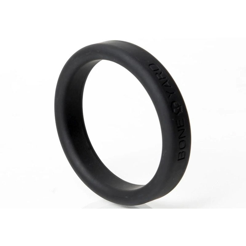 The Boneyard Silicone Ring 50mm - Black features a smooth texture and 3x-stretch flexibility with Boneyard embossed along the edge. Set upright on a plain white background, it casts a faint shadow, epitomizing the essential man toys style.