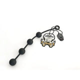 The Boneyard Ass Ballz M - Black 40 cm Medium Anal Balls feature five graduated spheres made from soft touch silicone, a circular handle, and include a skull-themed keychain with a yellow tag. Crafted from hypoallergenic material for comfort and safety, set against a plain white background.