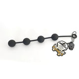 The Boneyard Ass Ballz L features four connected black spheres made of hypoallergenic, medical-grade silicone on a flexible rod with a loop handle. It includes a branded tag with a stylized skull design and text, presented against a white background.