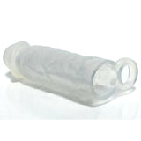 The Boneyard Meaty Cock Extender is a clear, cylindrical silicone sleeve with a textured surface and an extra loop or ring for added sensation, designed to encase or protect. It is shown laid horizontally on a reflective white surface.