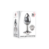 The image displays the Adam & Eve Clear Gem Anal Plug, a small 7.1 cm metallic butt plug made of body-safe polished aluminum. The box features a silver plug with a round clear jeweled base, highlighting its suitability for temperature play.