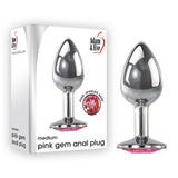 The image displays the Adam & Eve Pink Gem Anal Plug, a polished 8.2 cm medium-sized metal butt plug with a pink jeweled base. The packaging shows its design alongside the label Adam & Eve, describing it as a medium pink gem anal plug.