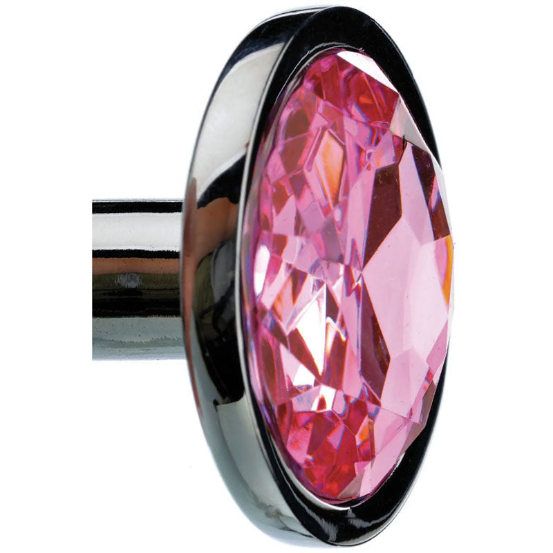 A polished aluminum Adam & Eve Gem Anal Plug - Medium - Silver showcases an oval-shaped, faceted pink gem in a round black setting. The gem sparkles as light reflects off it, contrasting beautifully with the shiny plug. The metal rod extends horizontally from the left side.