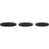 Three smooth black silicone penis rings from the Adam & Eve Silicone Penis Ring Set are displayed on a white background, highlighting their round shape and uniform color. Designed for comfortable and effective performance, these cock rings come in three sizes to help prolong erections.