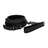 Explore the Adam & Eve Fetish Dreams Advanced Bondage Set, highlighting a chic black quilted vegan leather collar with a metal buckle and chain leash. Adjustable silver eyelets and a matching quilted handle on the leash add an elegant, padded look.