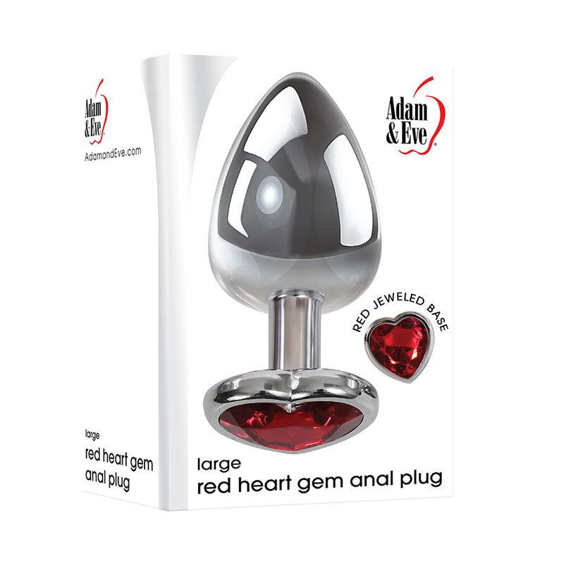 The image shows a product box for the Adam & Eve Red Heart Gem Anal Plug - Large. The aluminum plug features a heart-shaped gem base. The Adam & Eve logo is prominently at the top with descriptive text near the bottom.