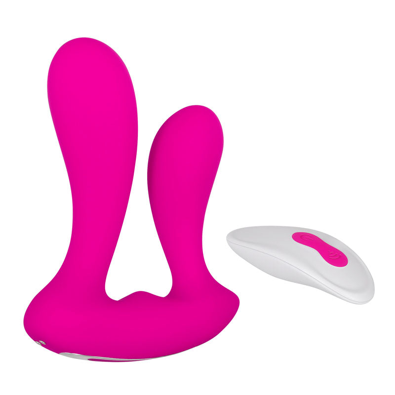 The Adam & Eve Rechargeable Dual Entry Vibe is a pink silicone toy for double penetration with a larger and smaller prong. It comes with a white wireless remote featuring two pink buttons, all set against a white backdrop.