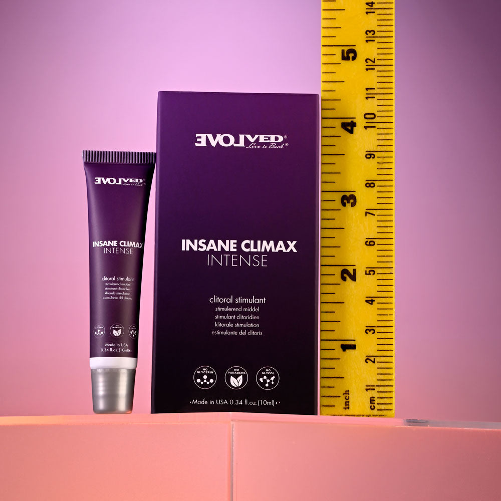 An Evolved Insane Climax - Intense clitoral stimulation gel, 0.34 fl oz (10 ml) tube, sits beside its purple box on a pink surface for enhanced pleasure. A yellow measuring tape with inch marks is displayed nearby. The packaging shows the reversed brand name Evolved at the top.