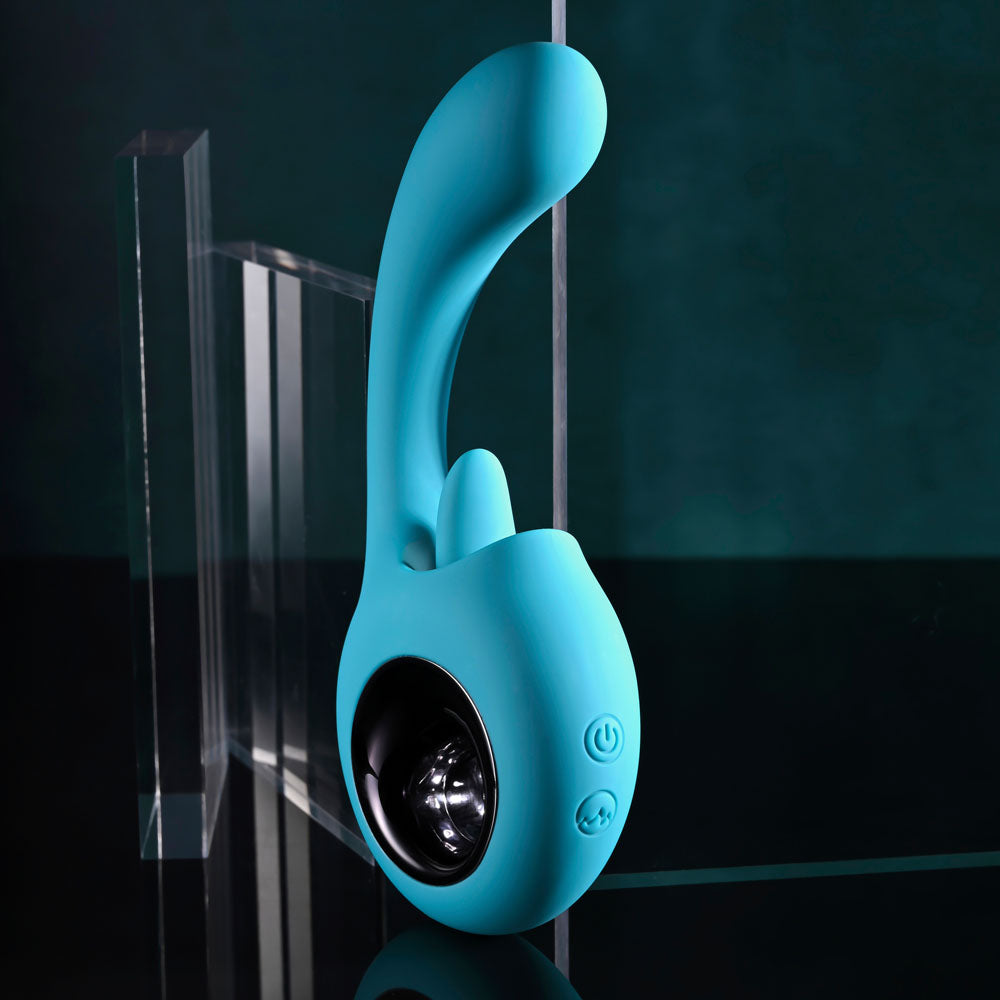 The Evolved HOW MANY LICKS is a blue, curved 17.8 cm USB rechargeable vibrator featuring G-Spot stimulation and two side buttons resembling a power symbol, with a reflective black circular base against a greenish-black background designed for ultimate pleasure.