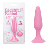 Next to the soft silicone butt plug stands its packaging, featuring the brand Beautiful Behind. The box showcases dimensions of 11.5 cm and highlights features like Strong Suction Cup Base and a Smooth Tip, with the product aligning perfectly in shape.