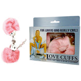 Love Cuffs - Pink Fluffy Hand Cuffs are displayed beside their packaging, ideal for adventurous lovers. The box shows a person in blue attire and highlights the product name, Love Cuffs, with the tagline, Adding a soft touch to the art of restraint.