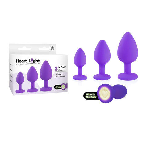 The image showcases the Heart Light set, featuring three purple silicone plugs with heart-shaped glow-in-the-dark bases. An inset highlights their enchanting glow, offering varied sizes in one charming package.