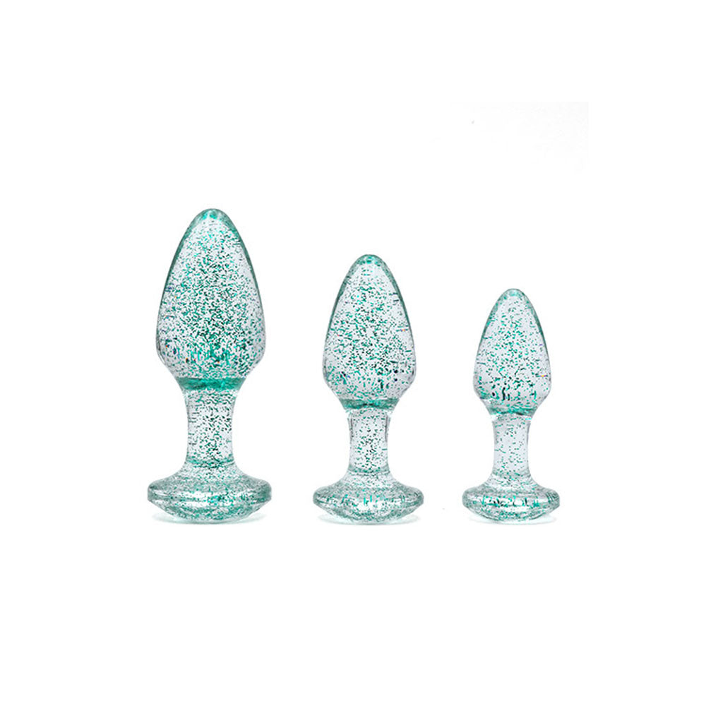 The Adam & Eve Glitter Gem 3-Piece Butt Plug Set in Glitter Blue features three translucent, teardrop-shaped plugs with a gem base. They are arranged from the largest on the left to the smallest on the right against a plain white background.