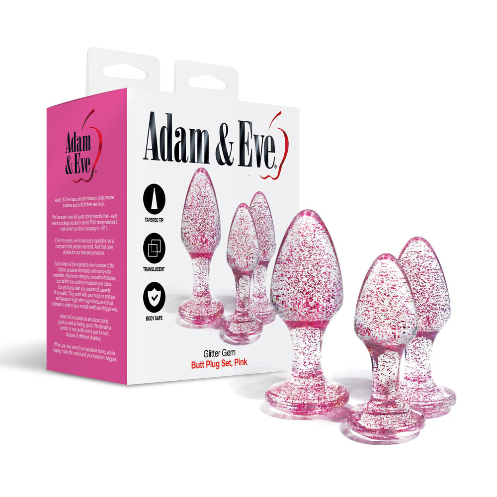 The image displays the Adam & Eve Glitter Gem 3-Piece Butt Plug Set in pink, with three translucent plugs featuring sparkly flakes and gem-shaped bases for anal training, placed beside their branded packaging.