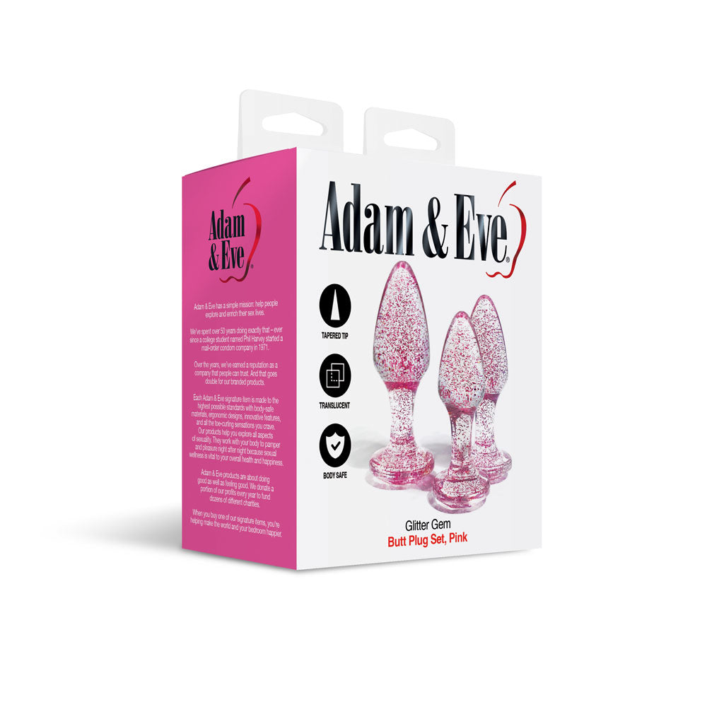 The packaging for the Adam & Eve Glitter Gem 3-Piece Butt Plug Set features three glitter pink plugs with tapered tops and gem-shaped bases. Highlighted as Body Safe and ideal for anal training, its elegantly depicted against a white backdrop with pink accents.