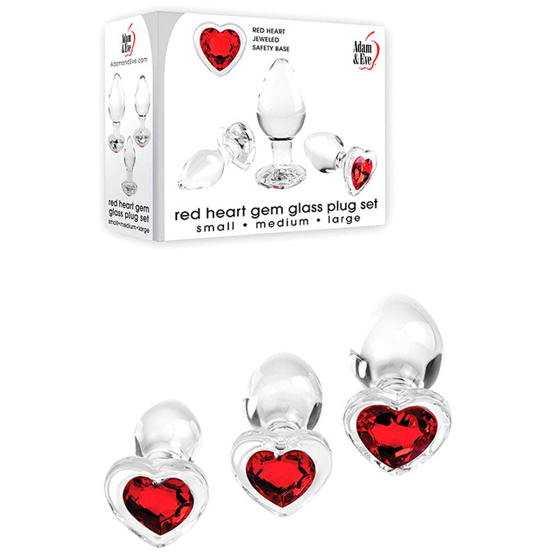 Three clear glass butt plugs with red heart-shaped gems are displayed in front of white packaging featuring their image and the text: Adam & Eve Red Heart Gem Glass Plug Set. Ideal for anal training or temperature play, sizes are labeled small, medium, and large. Brand logo is Adam & Eve.