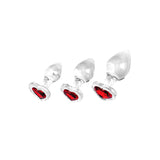 The Adam & Eve RED HEART GEM GLASS PLUG SET features three clear glass butt plugs with heart-shaped bases and a vivid red center, strikingly visible through the glass.