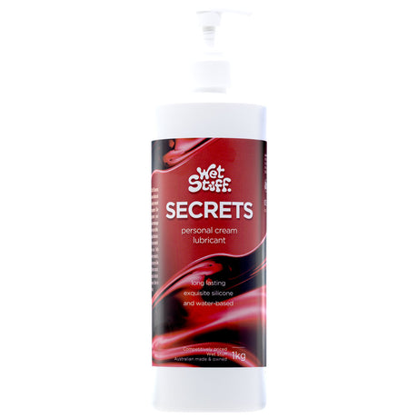 The Wet Stuff Secrets 1kg hybrid lubricant comes in a white pump bottle, featuring a creamy, moisturizing formula. The red label with black swirls and white text highlights its long-lasting silicone and water-based properties, condom compatibility, and 1 kg capacity.