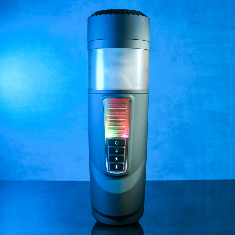 The Gender X MESSAGE IN A BOTTLE is a modern, cylindrical device with a transparent top showing a textured inner channel. The front panel includes a power button and red, green, yellow indicators. Its sleek blue surface adds a futuristic touch.