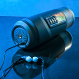 The Gender X MESSAGE IN A BOTTLE, a USB rechargeable thrusting & spinning masturbator, lies on a reflective surface, exuding modern vibes. Earbuds rest beside it as blue light bathes the scene, reminiscent of turbo mode ambiance enhancing its futuristic allure.