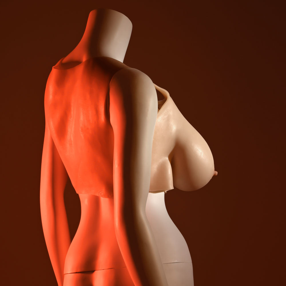 Two mannequins stand against a dark red background with their torsos overlapping. One displays the Gender X UNDERGARMENTS - PLATE E-CUP, featuring realistic E-cup enhancements facing forward, while the other turns away. Dramatic lighting emphasizes the smooth surfaces and bold contours.