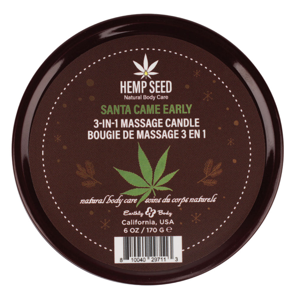 A round brown label for the Hemp Seed 3-In-1 Massage Candle - Santa Came Early (170 g) by Earthly Body, California, USA, shows a cannabis leaf icon, decorative leaves, text in English and French. Infused with hemp seed oil and labeled Natural Body Care.