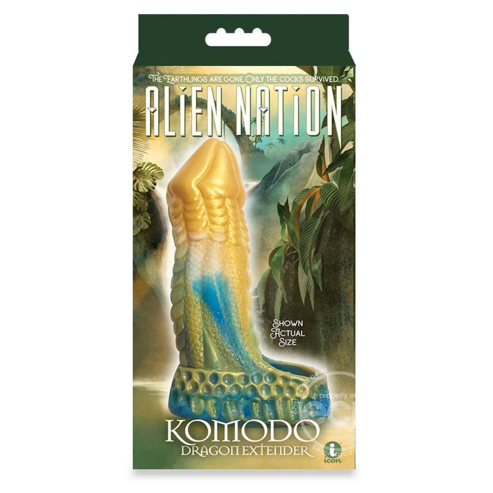 The Alien Nation - Komodo packaging features a dragon-themed penis extender in vivid yellow and blue, set against a green jungle backdrop. Text reads, The earthlings are gone, only the cocks survived, and Shown actual size.