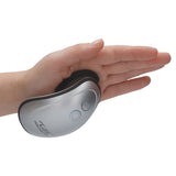 A hand holds a sleek silver Twitch 1 ergonomic device, designed to fit perfectly in the palm. It features a curved shape with thumb rest, illuminated power button, and textured base. ZeleSouris INNOVATION is printed on its side as a testament to its design excellence.