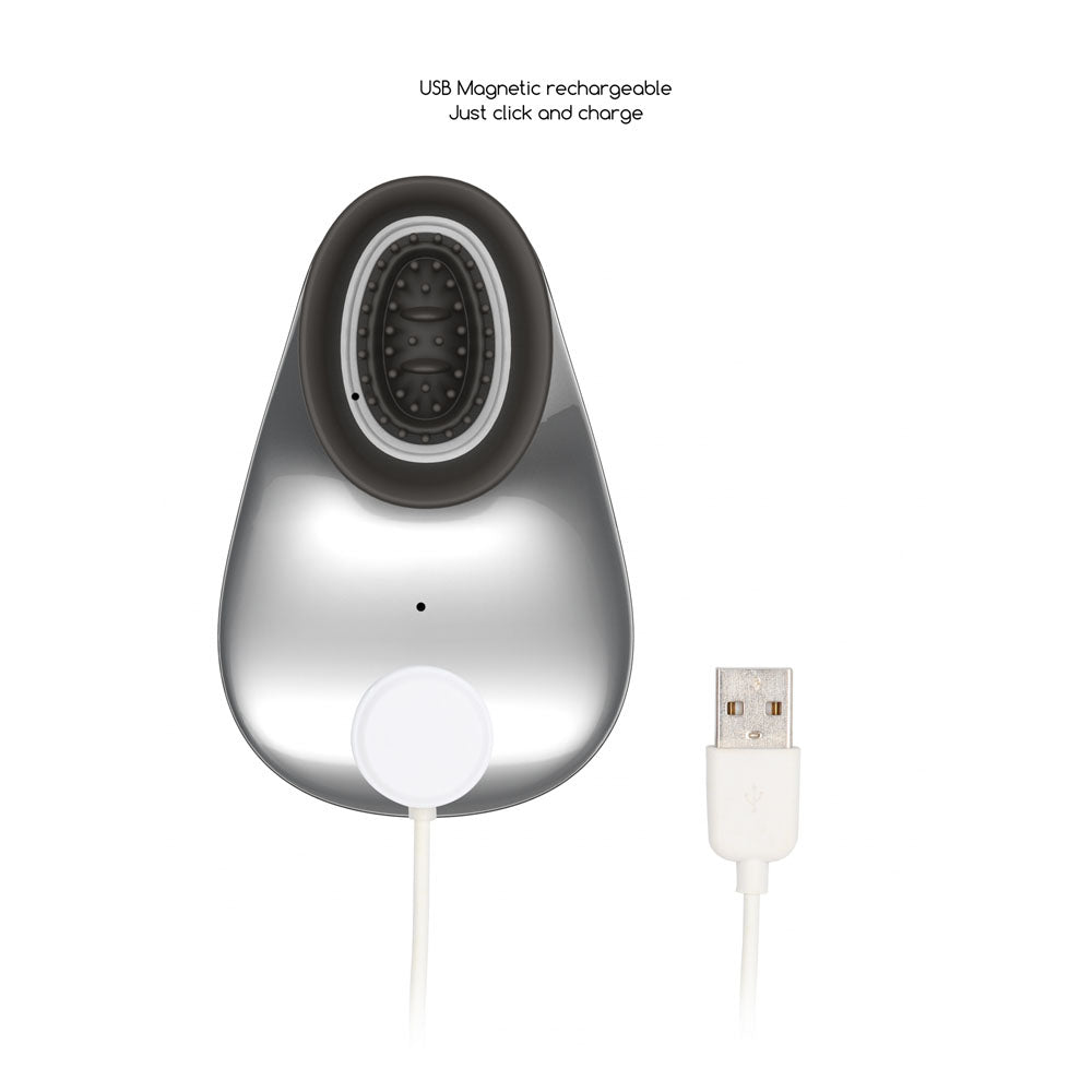 The Twitch 1 - Silver is an oval-shaped device featuring a black center ring with small nubs for enhanced clitoral stimulation. Equipped with a bottom USB magnetic charging cable, it offers seamless hands-free experiences. Text above reads USB Magnetic rechargeable Just click and charge.