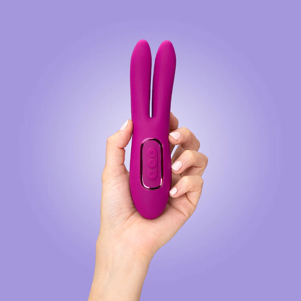 A hand holds the luxurious JimmyJane Solis Ascend 2 PRO, a purple 16 cm USB rechargeable dual tip stimulator, against a light purple backdrop. Its flexible design ensures intense stimulation with three-button central control and sleek, modern aesthetics.