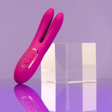 The JimmyJane Solis Ascend 2 PRO, a purple dual-tip stimulator made of smooth silicone, is upright against clear acrylic blocks on a reflective purple surface. The background gradient of purple adds a modern and elegant touch.