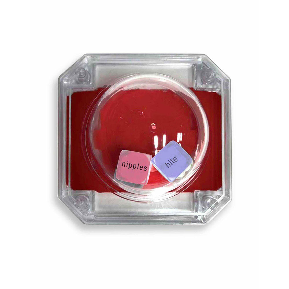 The Kinky Sex Pop dice game features a clear octagonal container with two pastel dice: a pink one labeled nipples and a blue one labeled bite, ideal for steamy play. The transparent lid reveals the dice set against a red background, enhancing its seductive appeal.