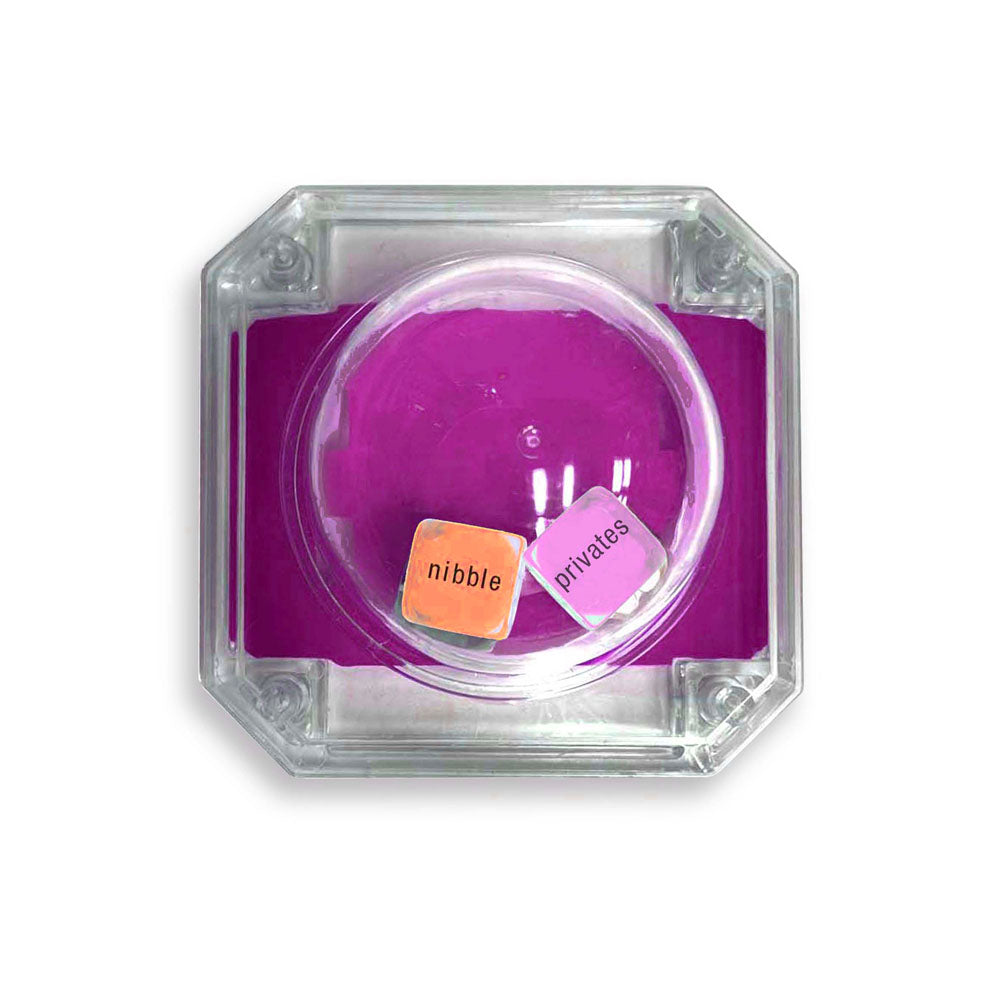 The Oral Sex Pop - Popping Dice Game features a clear container with a pink base, housing two popping dice: one orange die labeled nibble and one white die labeled privates, perfect for spicing up your intimate moments.